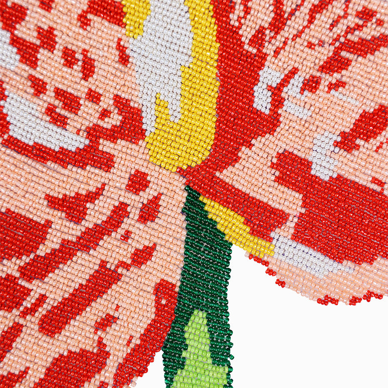 Close-up of a beaded design with red, yellow, and green colors on a white background