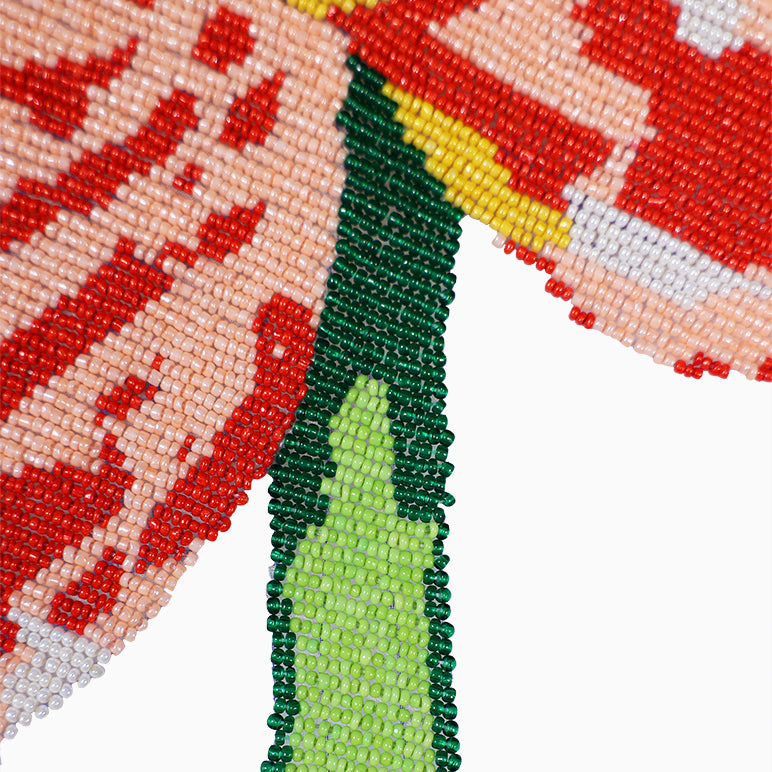 Close-up of a beaded design with red, green, and yellow patterns on a white background