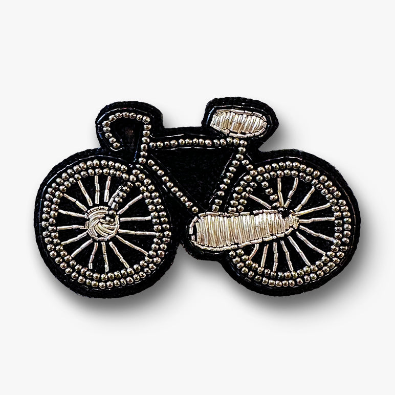 Decorative handmade bicycle brooch pin with black and silver color on a white background.