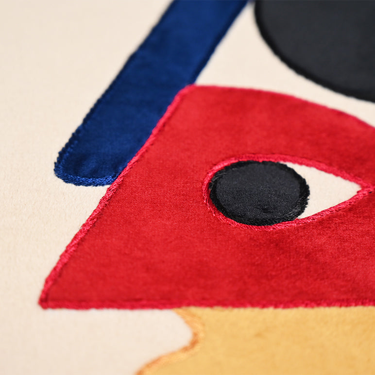 Close-up of a colorful abstract design with red, blue, and black colors on a beige background.