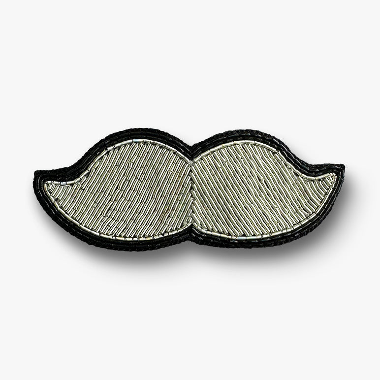 Hand embroidered Moustache-shaped brooch pin in silver and black on a white background