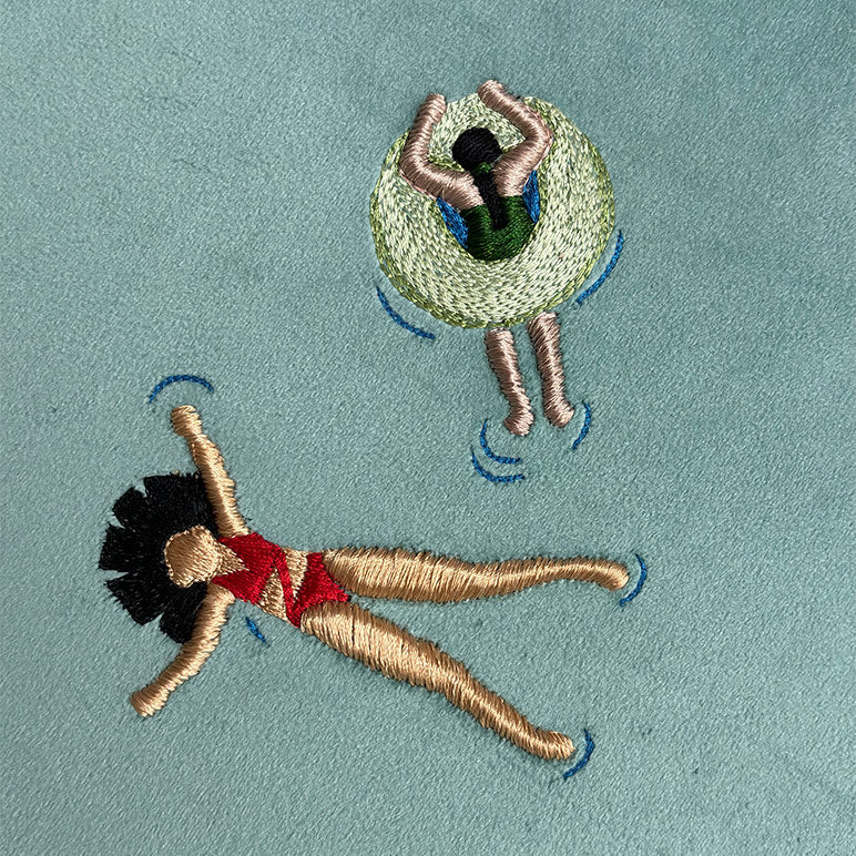 Embroidered design of a woman and a child on an inner tube against a light blue background