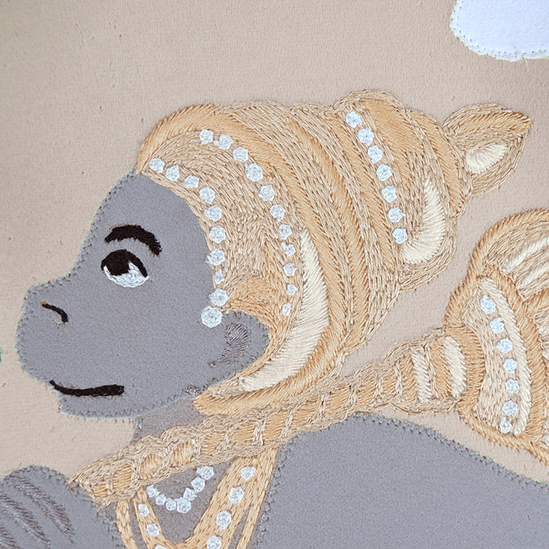 Embroidered design of a monkey with decorative headgear on a beige background