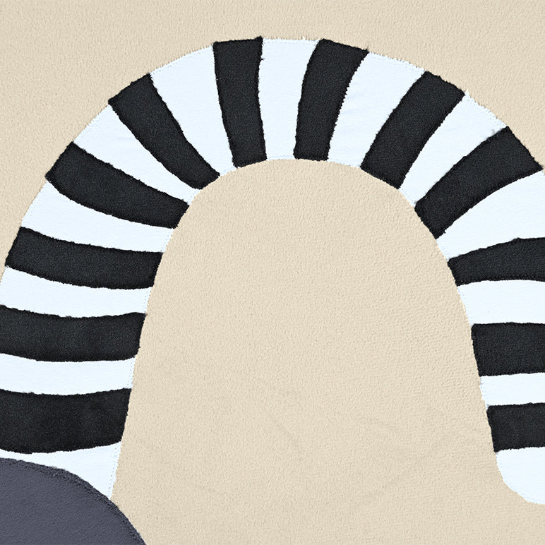 Round rug with black and white striped border on a beige floor