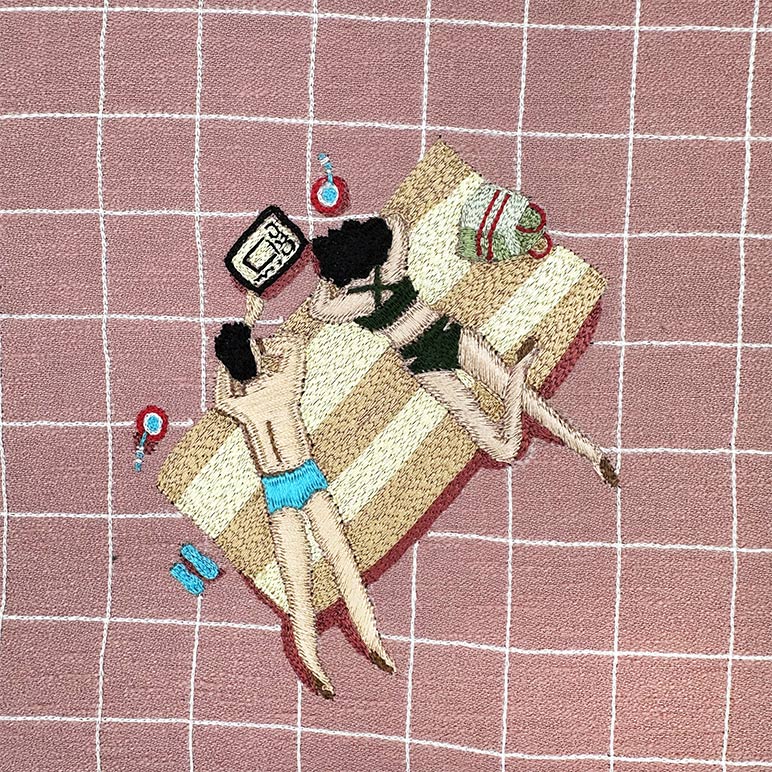 Embroidered design of a person lounging on a towel with beach accessories on a grid background