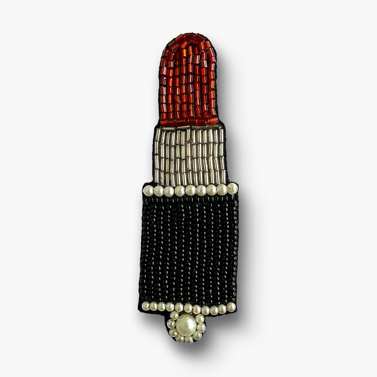 Beaded lipstick-shaped brooch on a white background