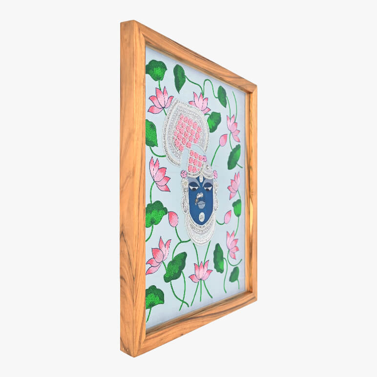 Framed artwork with a face design surrounded by pink lotus flowers and green leaves on a white background.