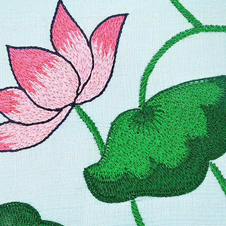 Embroidered pink flower and green leaves on a light blue background