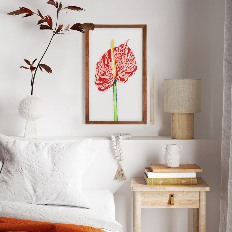 Decorative bedroom with a bed, nightstand, lamp, and wall art.
