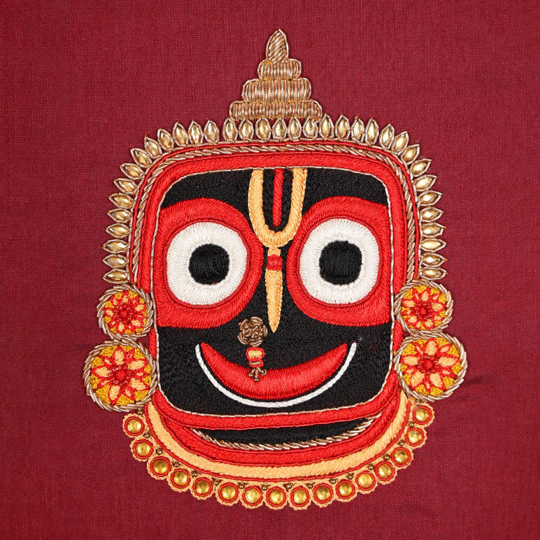 Embroidered face design with red, black, and gold colors on a red background