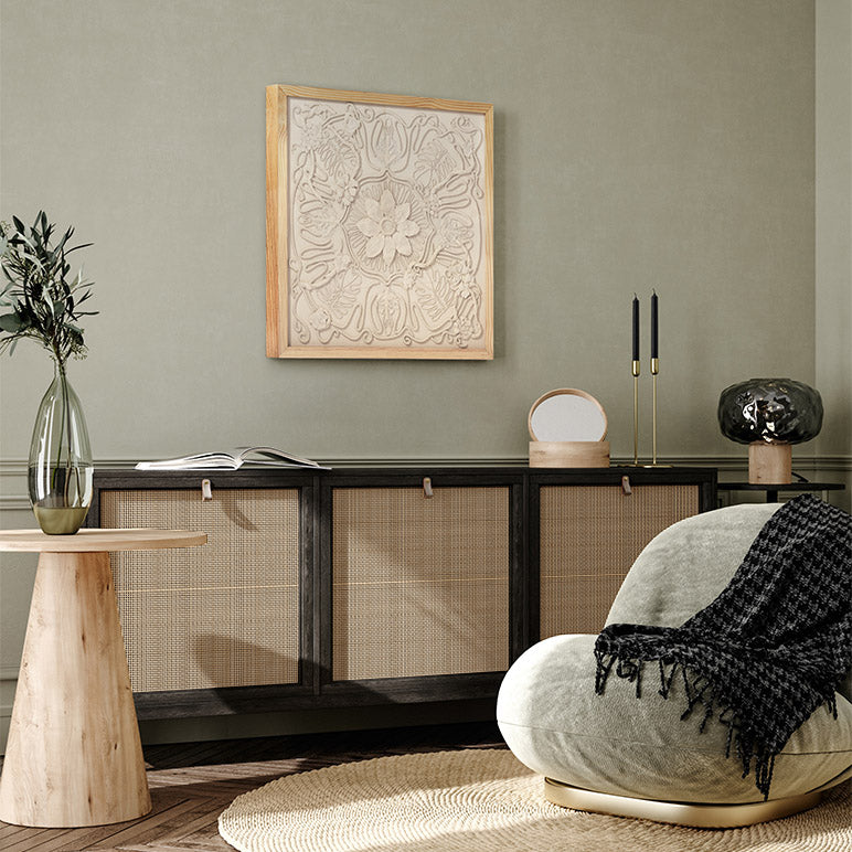 Modern interior with a textured wall art piece, wooden side table, and armchair with a blanket.