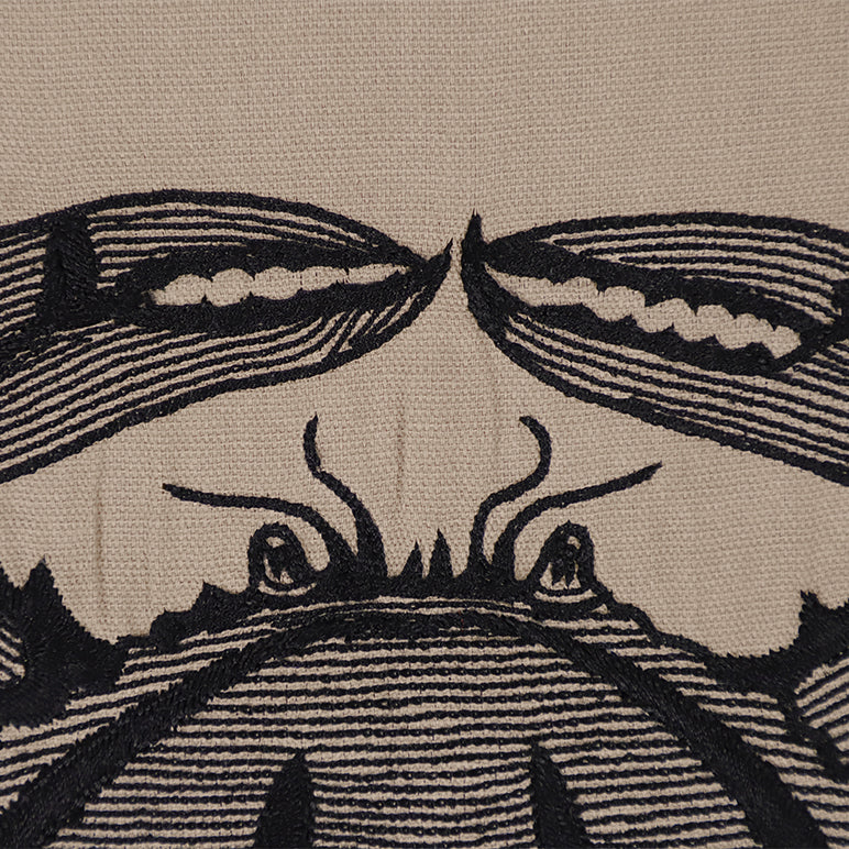 Close-up of a textile pattern with a stylized face design.