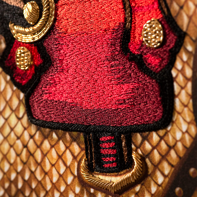 Close-up of a horse textile artwork with red and gold accents hand-embroidered