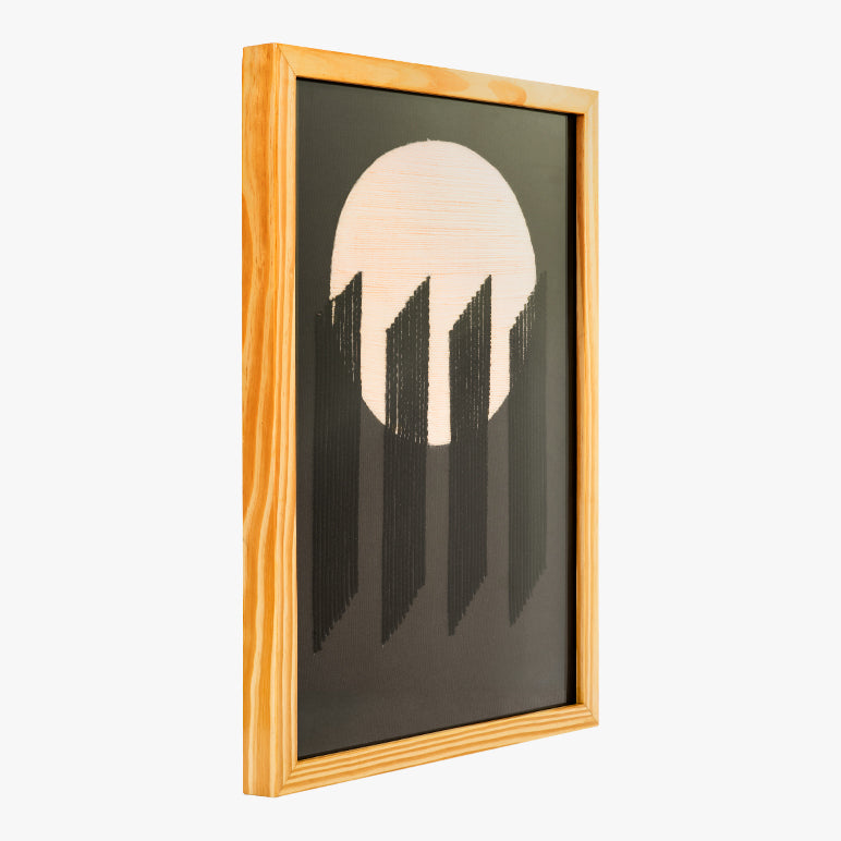 Framed artwork with a stylized depiction of a mountain range and a circular shape on a black background.