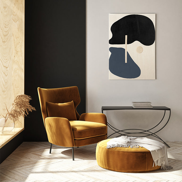 Modern living room with a mustard yellow armchair and ottoman, abstract art on the wall.
