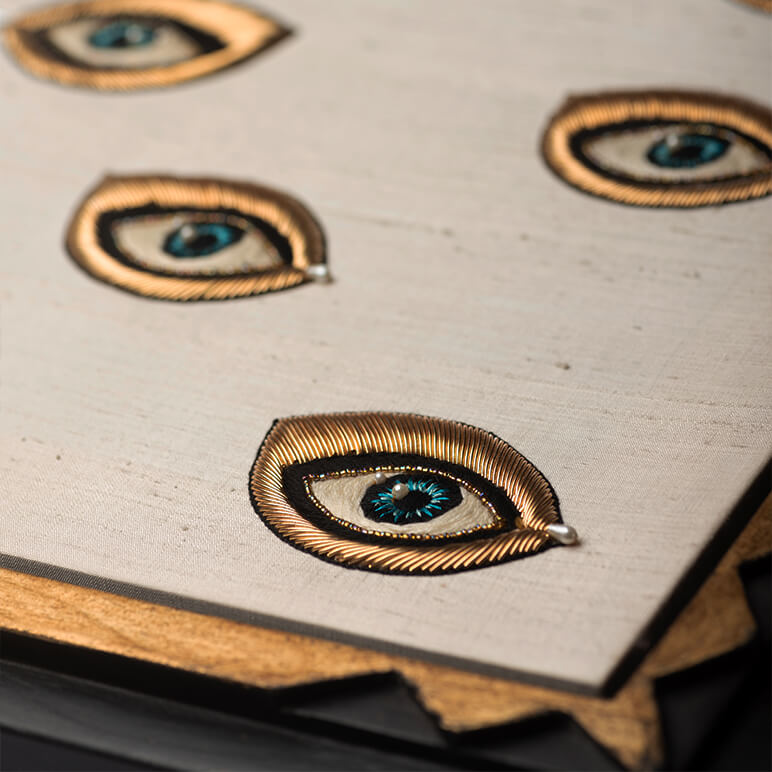 Close-up of decorative eye-shaped pins on a textured surface