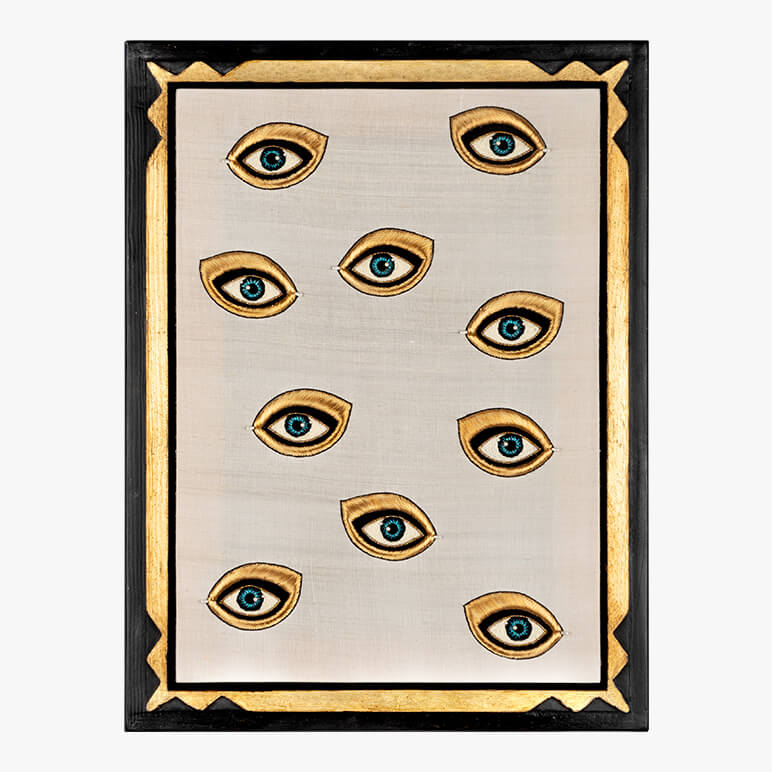 Decorative textile wall art with eye designs on a beige background