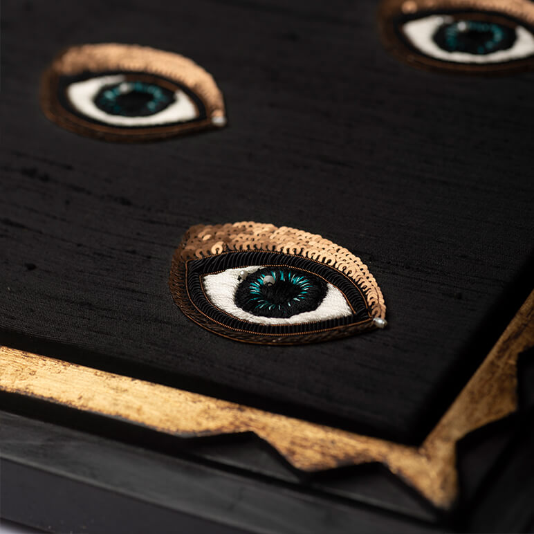 Close-up of embroidered eye designs on a black fabric background