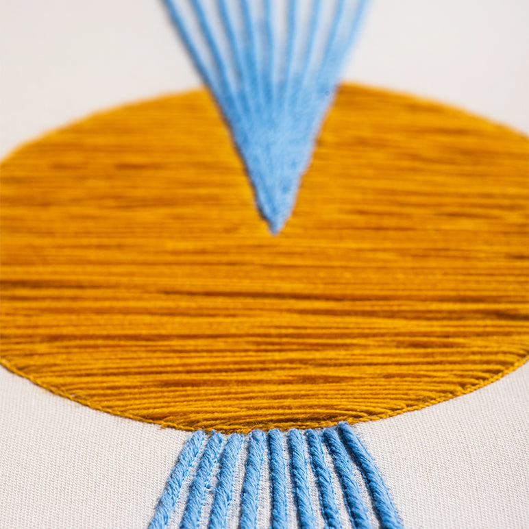 Close-up of a textile piece with orange and blue patterns on a white background