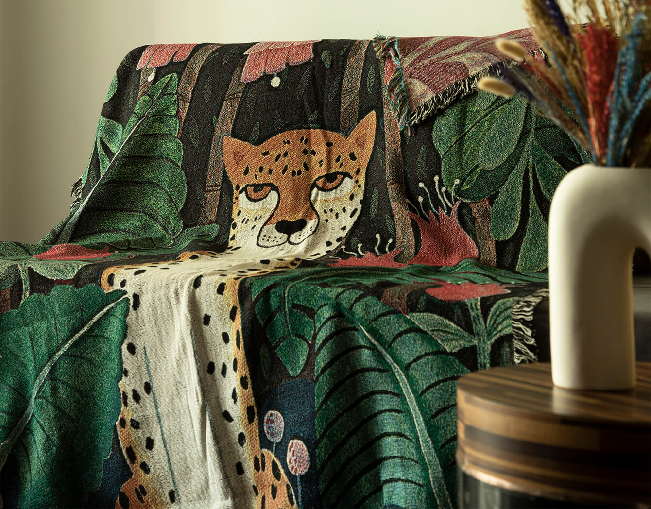 Decorative blanket with a cheetah design on a couch with leaf patterns.