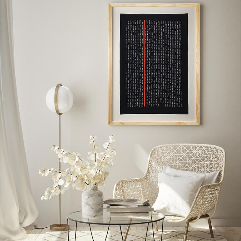 Modern living room with a framed artwork, wicker chair, and decorative table.