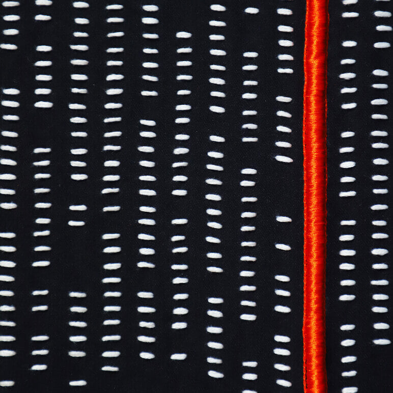 Close-up of a fabric with white vertical stitching lines on a black background and a red stripe.