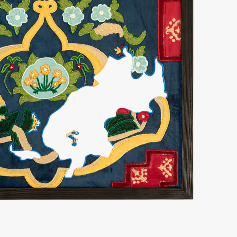 Embroidered design of a white cat on a blue background with decorative elements.