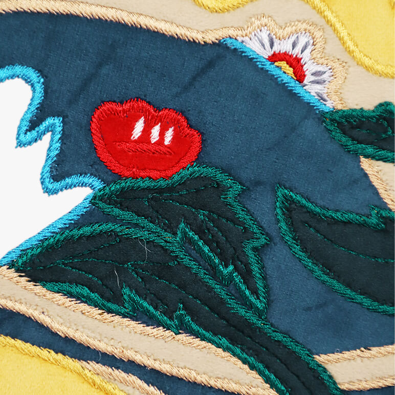 Close-up of embroidered fabric with red flower and green leaves on a blue background
