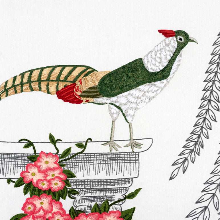 Embroidered design of a peacock with flowers and leaves on a white background