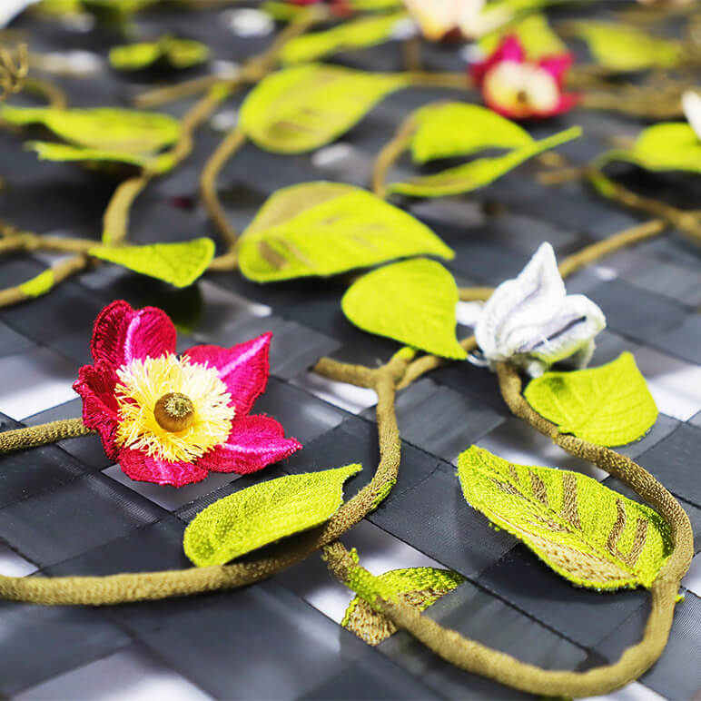 Floral headbands with pink, yellow, and white flowers on a woven surface