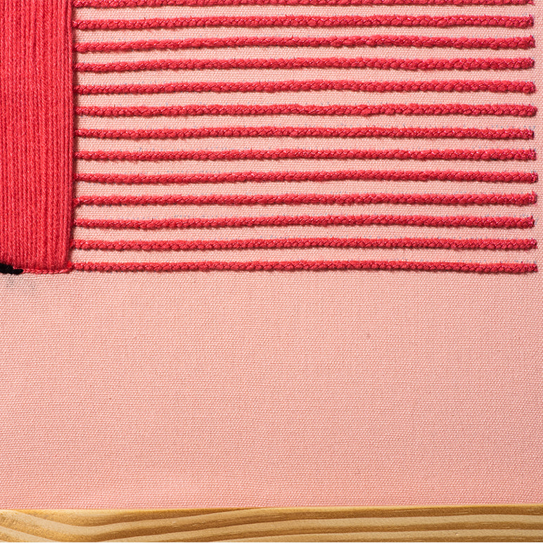 Close-up of a pink fabric with textured pattern and wooden surface at the bottom.
