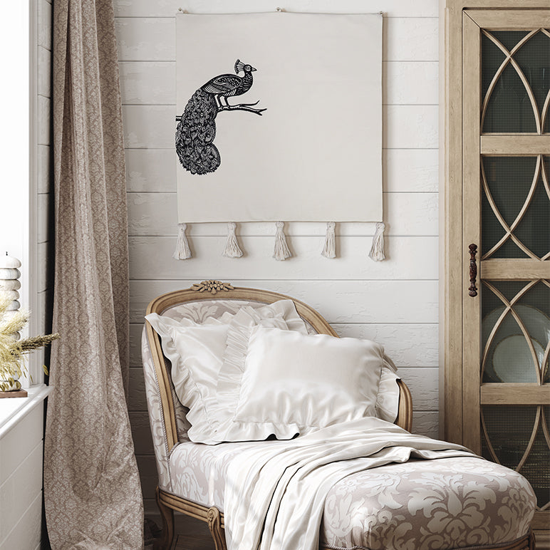 Decorative chair with pillows and a peacock wall hanging in a room setting.