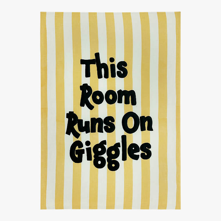 Striped playful nursery wall decor with the text "This Room Runs On Giggles" embroidered on it