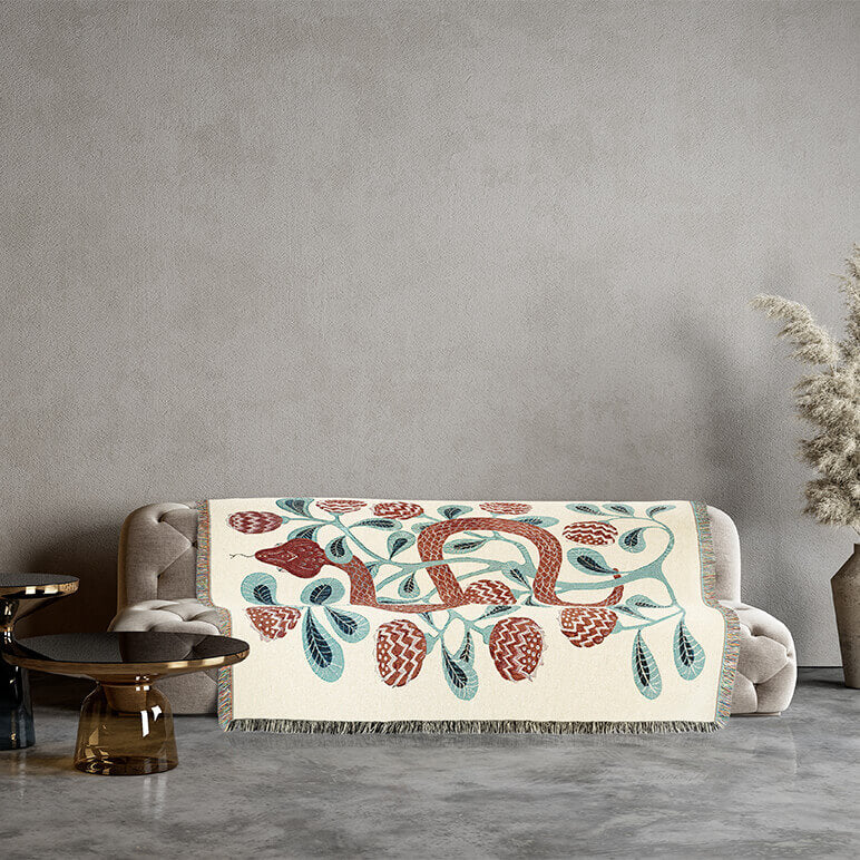 Decorative cotton blanket with a snake design on a sofa against a gray wall.