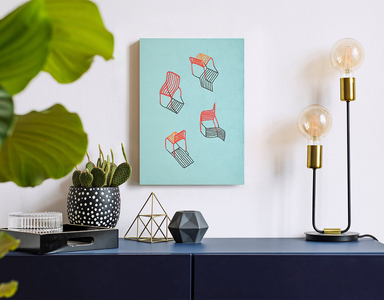 Modern interior decor with a lamp, plant, and abstract art on a wall.