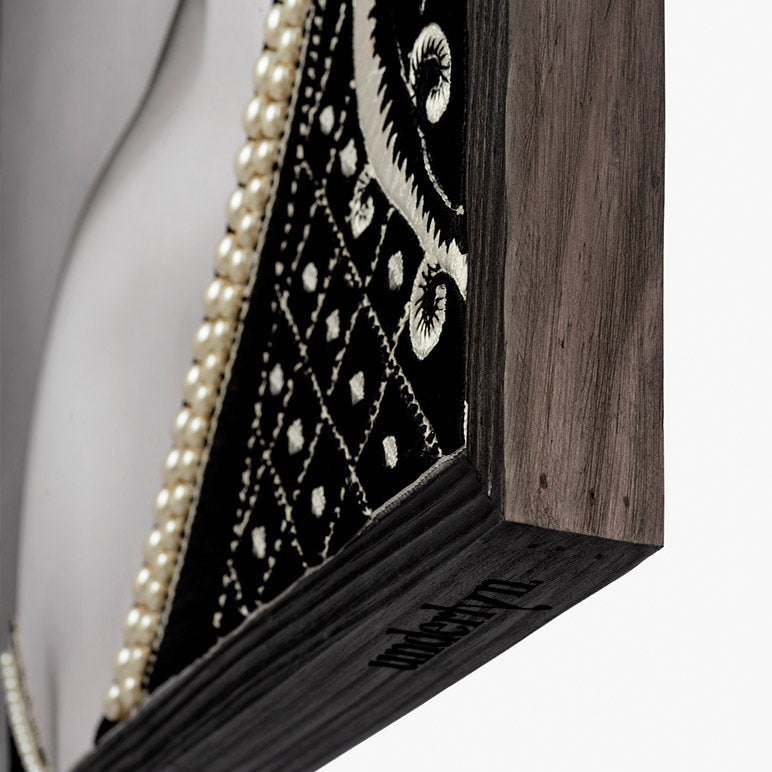 Wooden frame with black and white patterned fabric and pearl trim on a white background