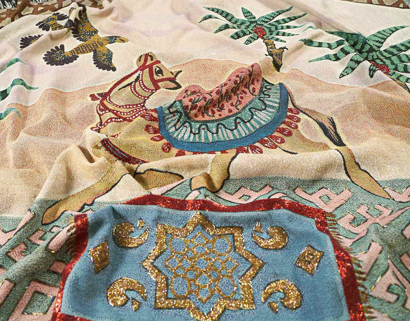 Embellished designer cotton throw blanket with a camel, a carpet and pine trees on a desert background