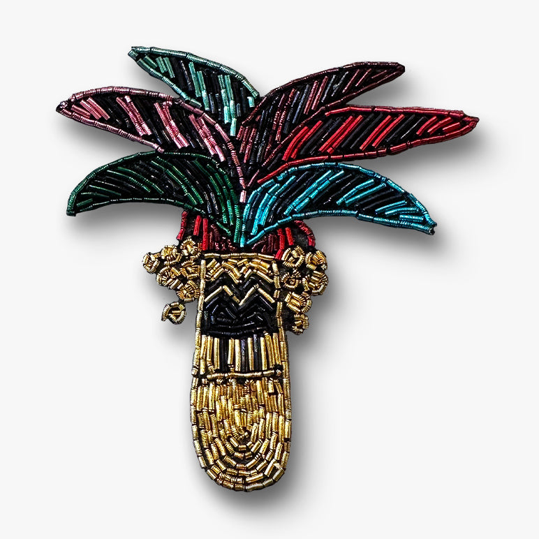 Decorative brooch with palm leaf design on a white background