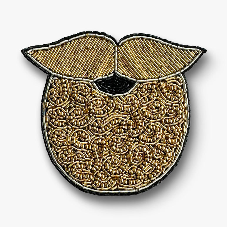 Decorative gold beard brooch pin with intricate patterns on a white background
