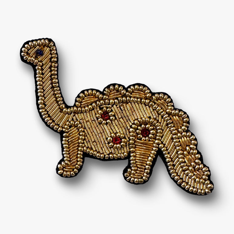 Gold dinosaur brooch hand-embroidered on a white background