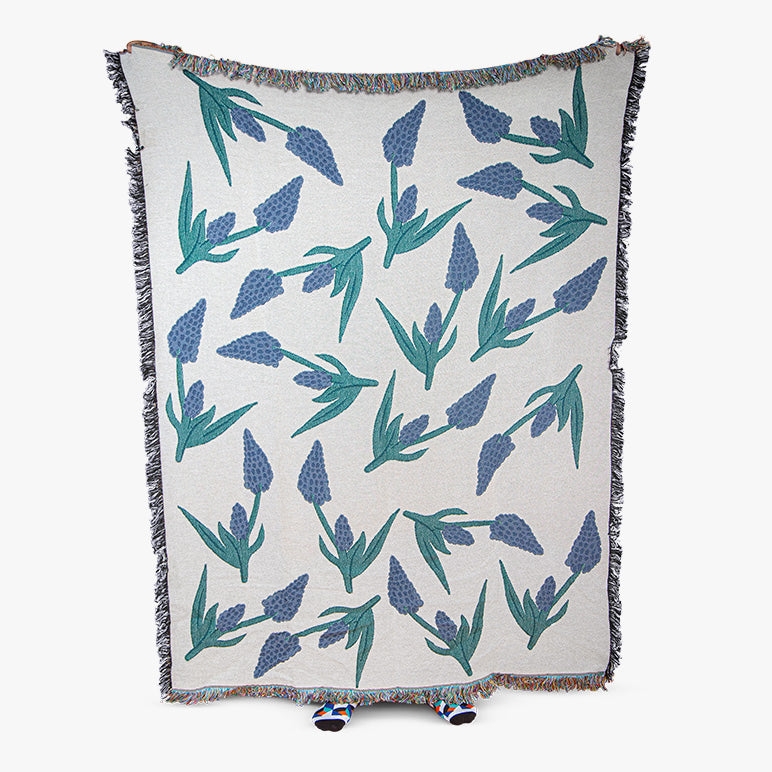 Floral patterned throw blanket with blue and green flowers on a white background