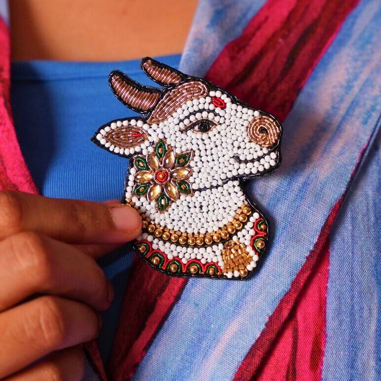 Decorative brooch shaped like Nandi held against a colorful fabric background