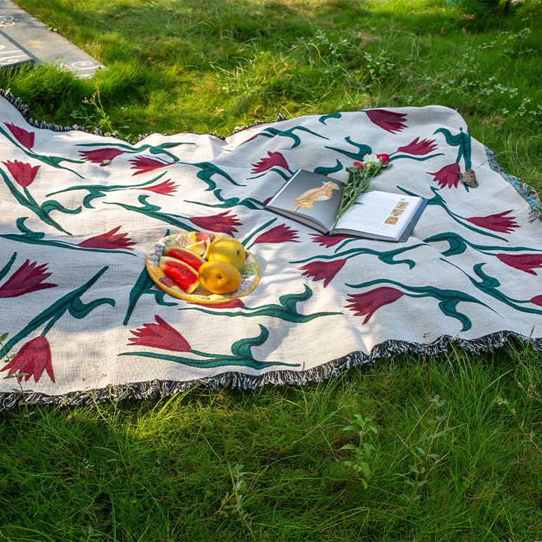 Decorative picnic blanket with floral patterns on grass