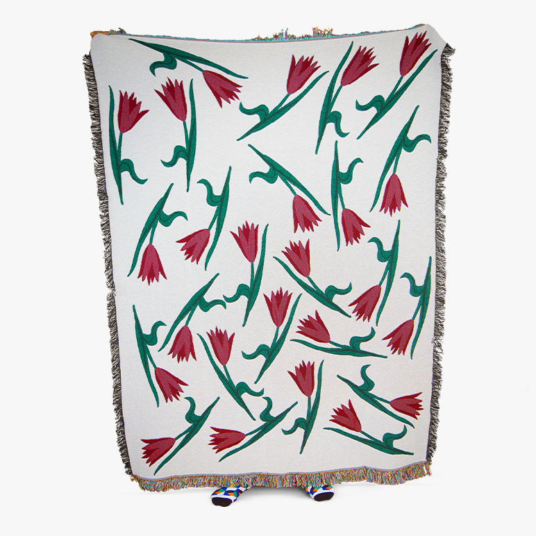 Blanket with red and green tulip floral pattern on a white background