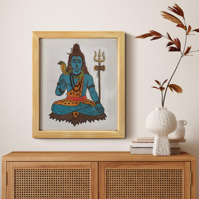 Framed artwork of Hindu deity Shiva on a wall above a wooden cabinet with decorative items.