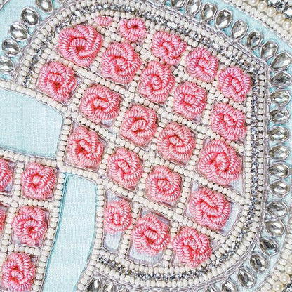 Close-up of a decorative item with pink floral patterns and a silver border.
