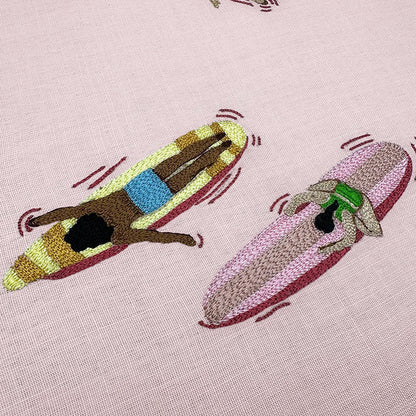 Embroidered design of a dog on a banana boat with another dog on a pink background