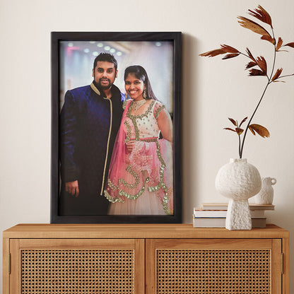 Framed portrait of a couple on a wooden cabinet with decorative items.