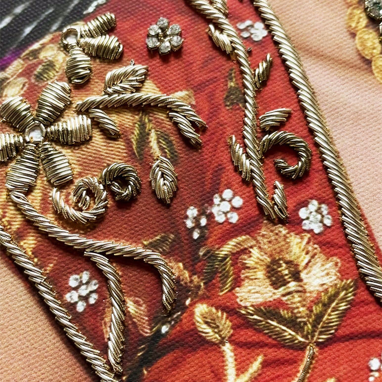 Close-up of gold embroidery on a fabric with floral patterns