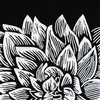 Close-up of an embroidered wall hanging with black and white floral pattern of succulent leaves on a black background